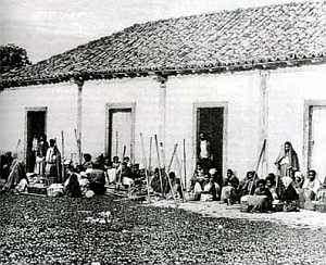 Foto do século XIX mostrando alguns escravos diante da senzala. Possivelmente essa senzala fosse de uma fazenda de café. 